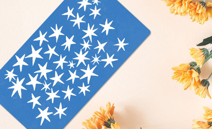 A blue card with a starry pattern lays on a table next to yellow daisies.